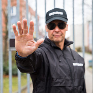 Security Guard Making Stop Gesture In Front Of Gate