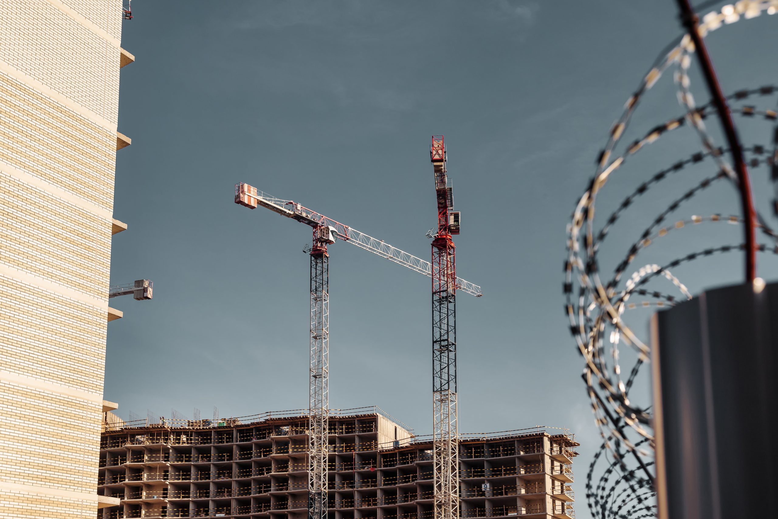 Construction cranes work on creation site against sky background