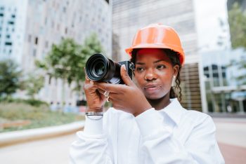 Serious black female photographer using camera on street